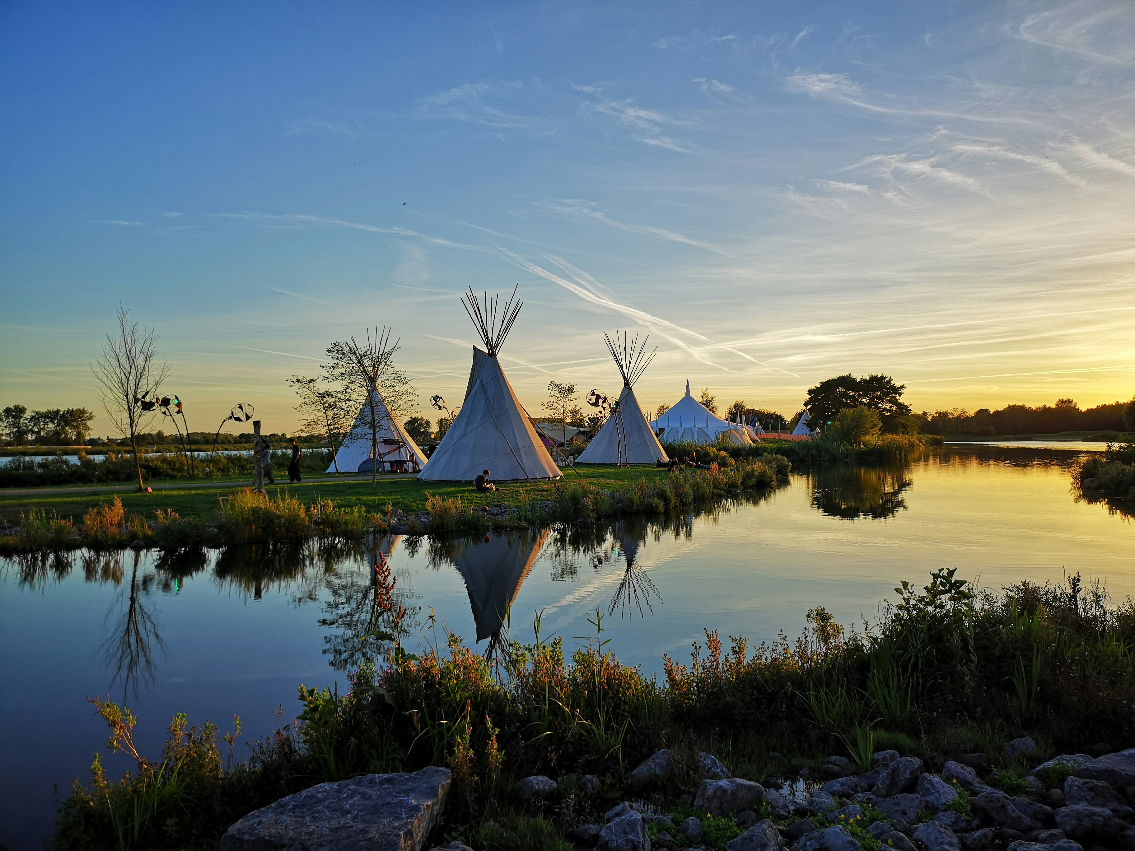 tipi tents on grass field near stream