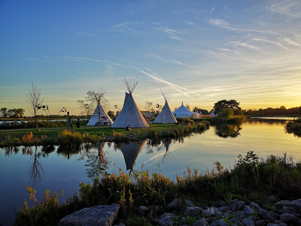 tipi tents on grass field near stream