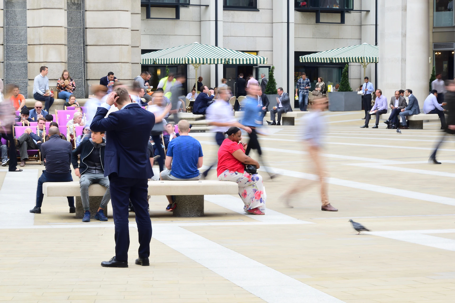 A lively snapshot of the plaza's central area featuring decorative plants and benches where people relax and chat.