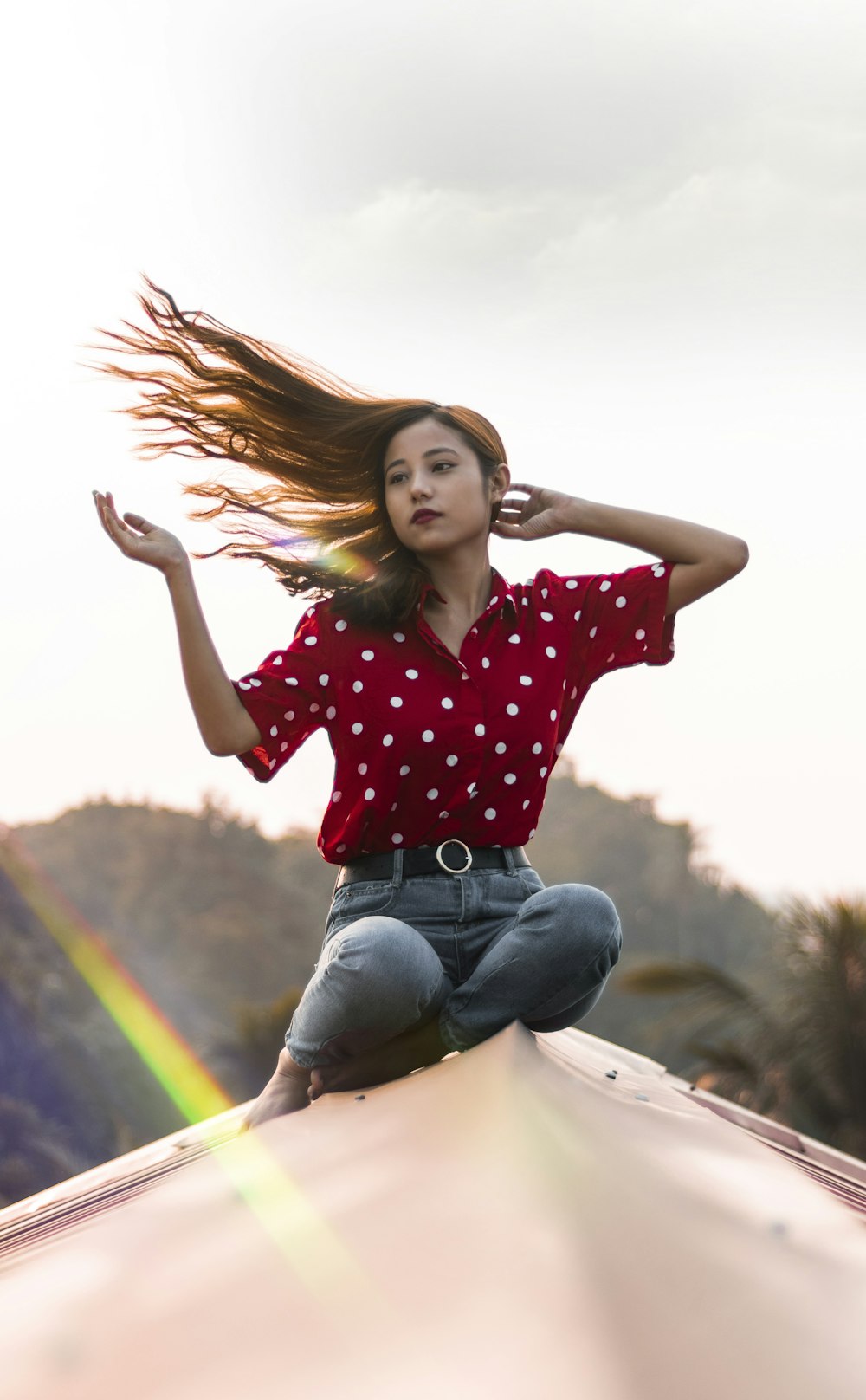 one unknown celebrity in red and white polka-dot top sitting under white sky