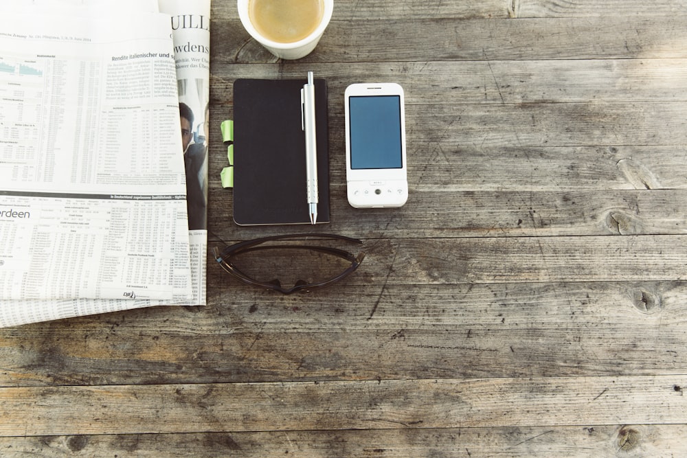 stylo à côté du téléphone portable sur une surface en bois