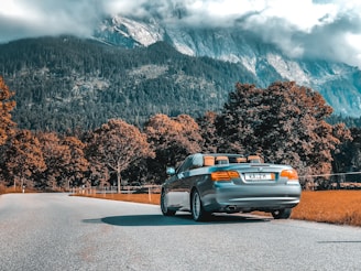 A convertible car with the top down on a scenic road.