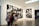 A gallery with modern art photographs displayed on white walls, featuring large black and white images with various abstract and surreal elements. Several people are walking past, slightly blurred, indicating motion.