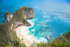 an aerial view of a sandy beach with two large rocks sticking out of the water