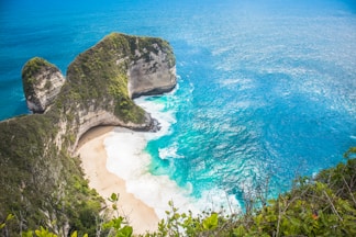 an aerial view of a sandy beach with two large rocks sticking out of the water