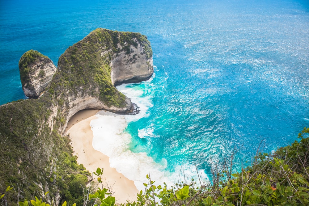 an aerial view of a sandy beach with two large rocks sticking out of the water