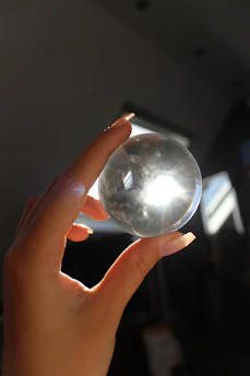 Close-up of hands holding a glowing crystal ball surrounded by softly glowing numerology charts.