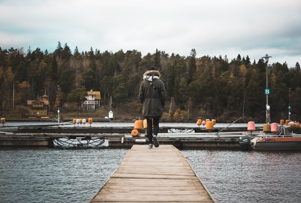 person walking on brown wooden boardwalk