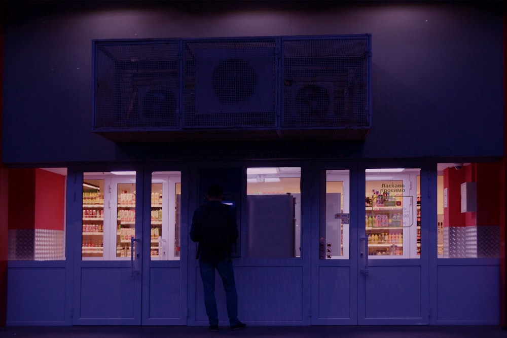 um homem em pé na frente de uma loja à noite