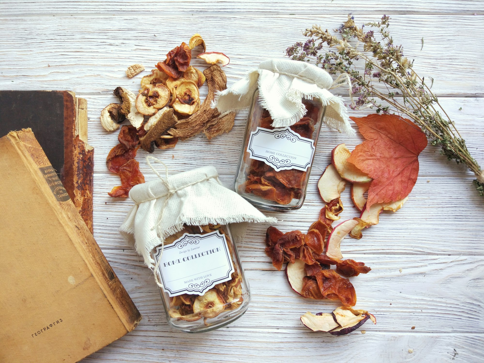 Rustic autumn composition with dried fruits in a glass jars and vintage labels on white wood background, harvest concept, healthy preserved food. Top view