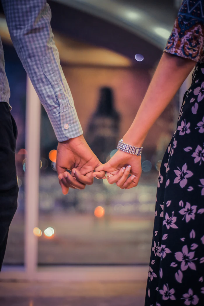 Hai bàn tay nắm nhau trước những vệt sáng nhoè của thành phố