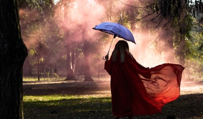 woman holding blue umbrella artificial tree teams background