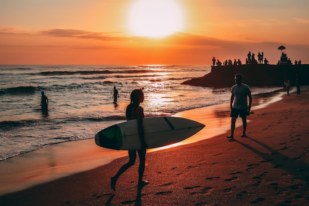 gente en la playa durante la puesta de sol ]