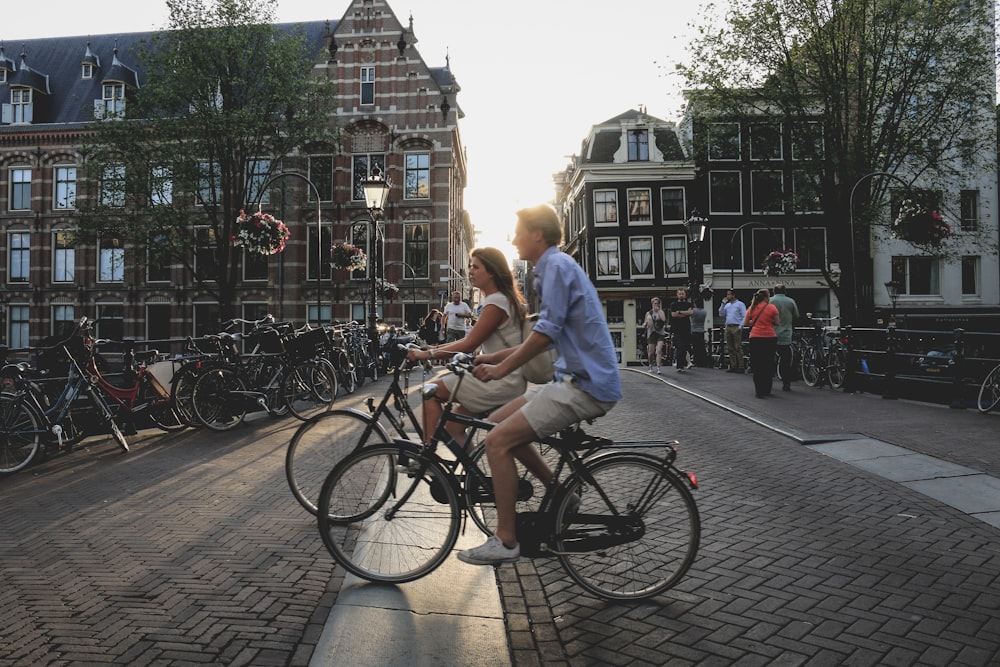 homme et femme faisant du vélo le long de la ville pendant la journée