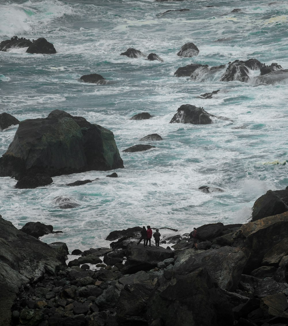 Un paio di persone in piedi sulla cima di una spiaggia rocciosa