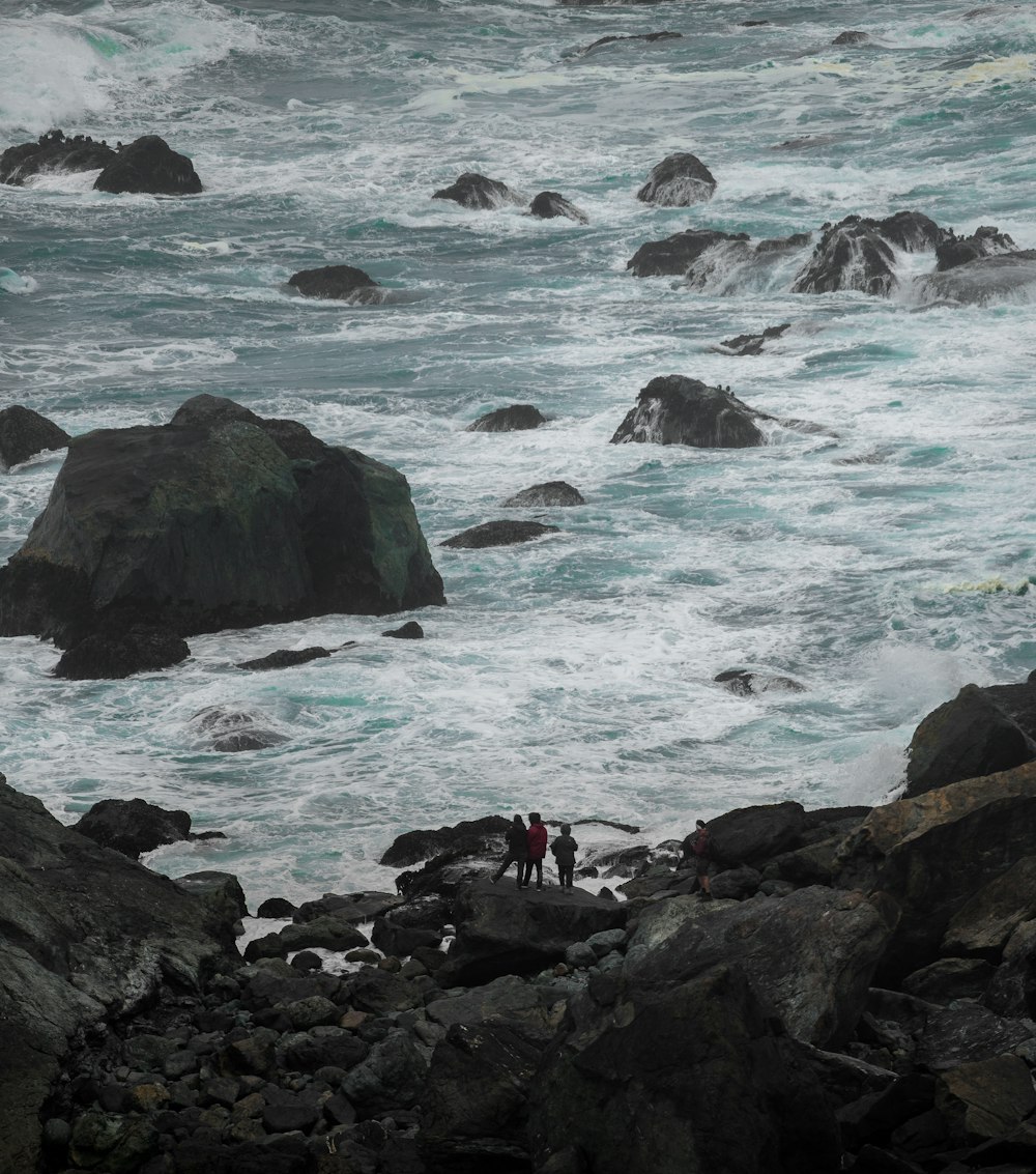 a couple of people standing on top of a rocky beach