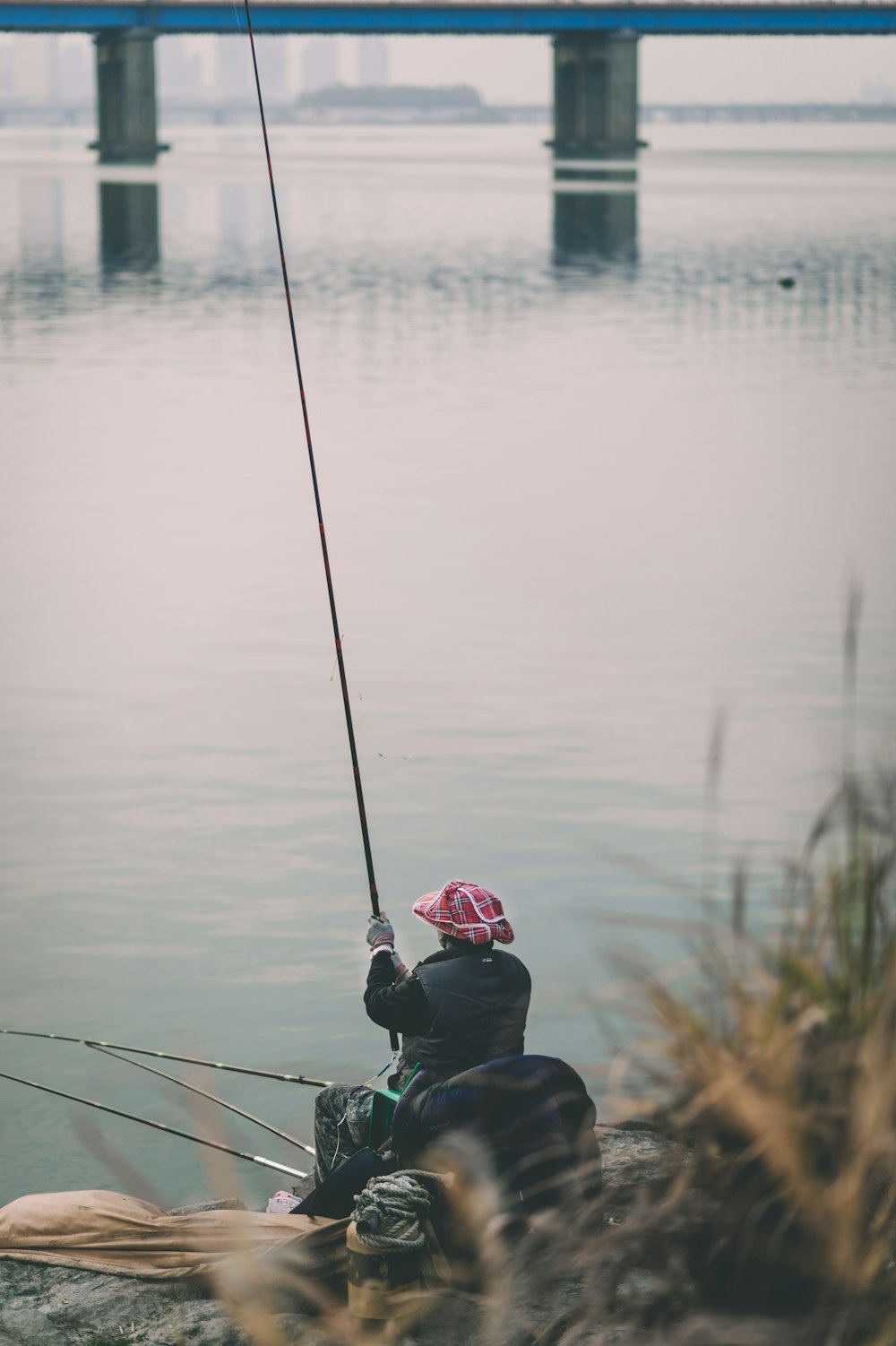person holding fishing rod beside body of water