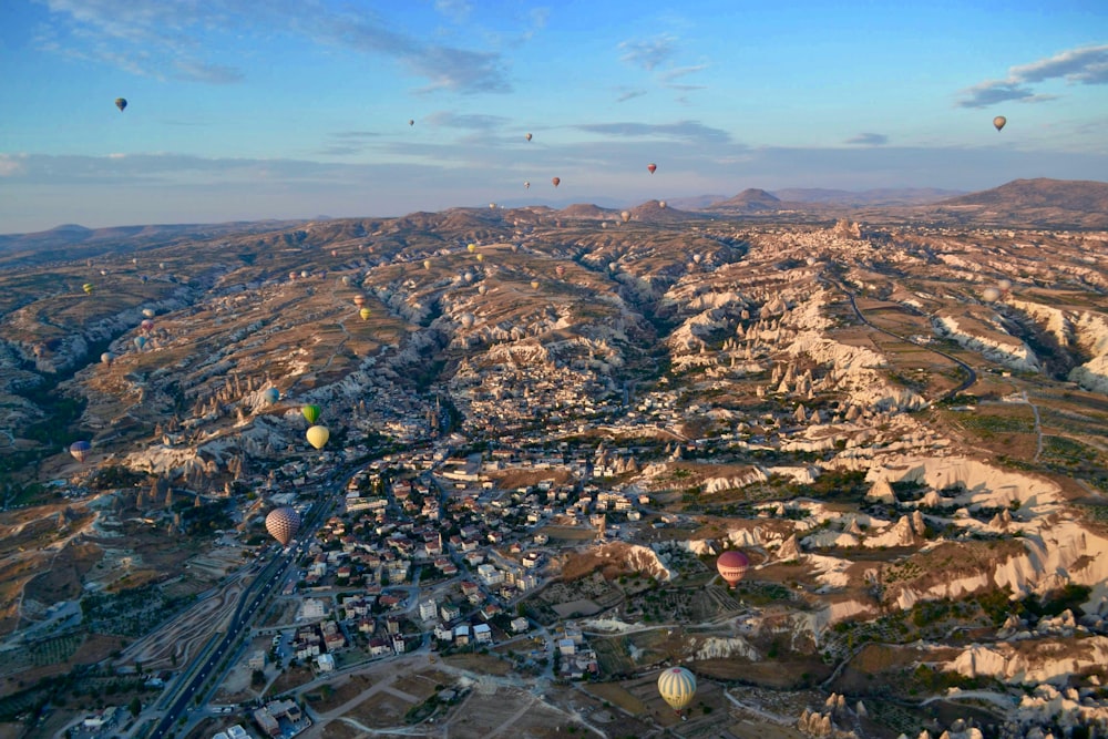 aerial photography of village with hot air balloon flying on sky