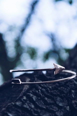 A bold copper cuff bracelet resting on a weathered wooden surface.