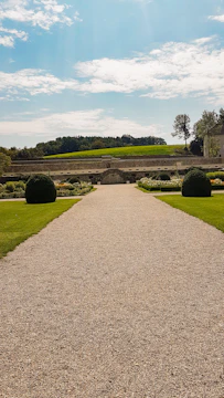 A freshly graded residential gravel driveway bordered by green lawns under a clear sky.