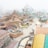An amusement park under construction featuring winding roller coaster tracks and artificial rocky landscapes with a misty atmosphere. Buildings and scaffolding are visible, along with pathways and pools of water.