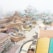 An amusement park under construction featuring winding roller coaster tracks and artificial rocky landscapes with a misty atmosphere. Buildings and scaffolding are visible, along with pathways and pools of water.