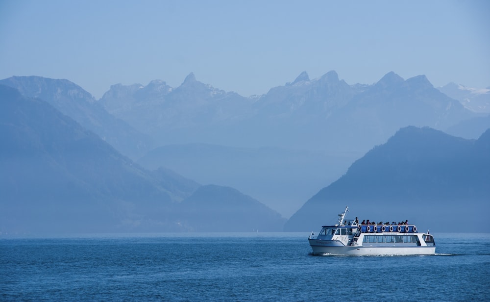white ferry sailing at sea near mountainous shore