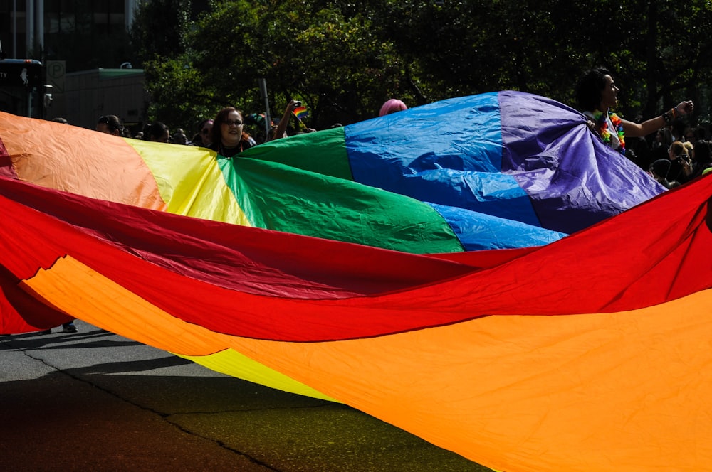 people holding multicolored tarpaulin during daytime