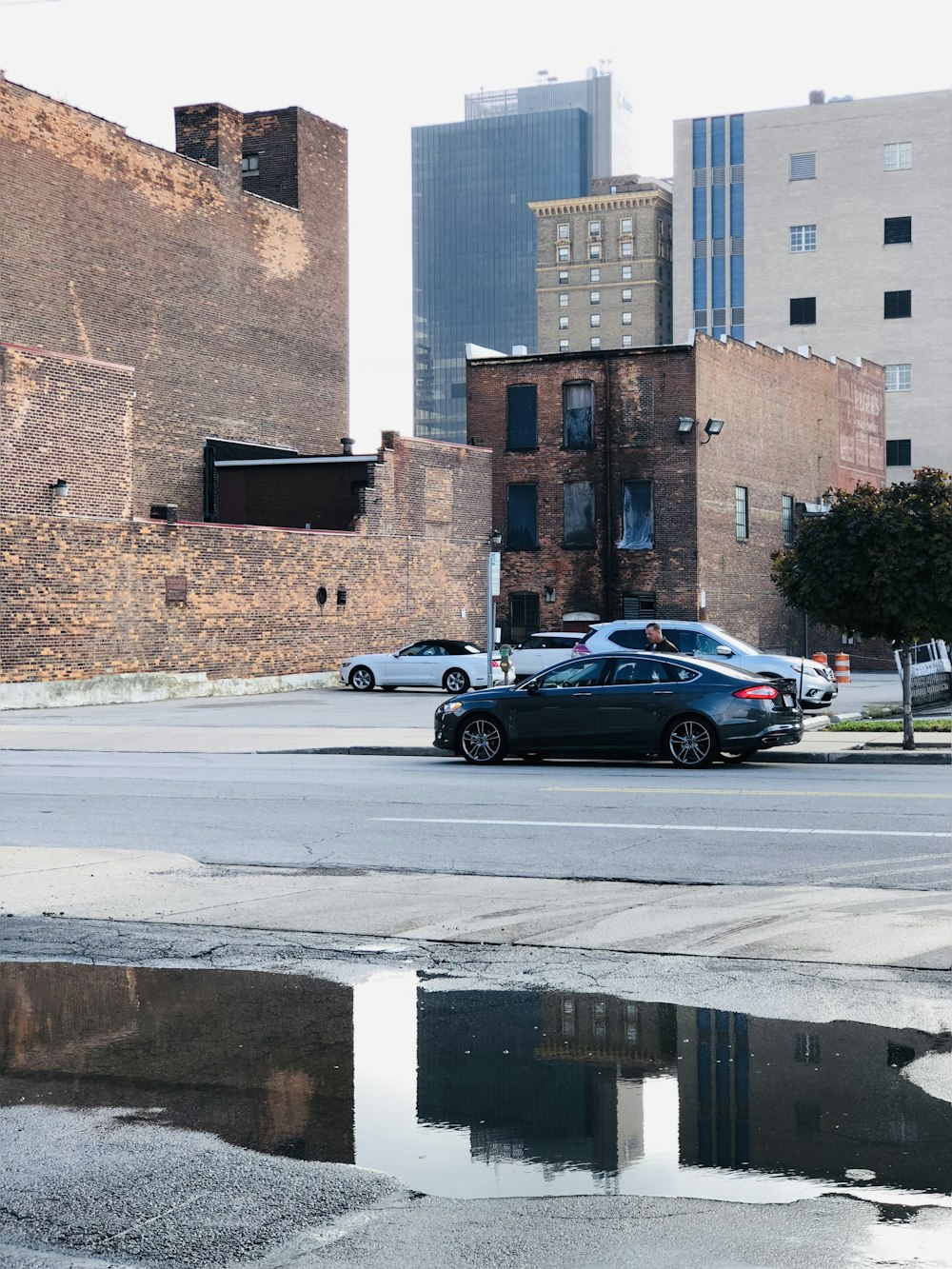 gray sedan parked on roadside near parking lot during daytie