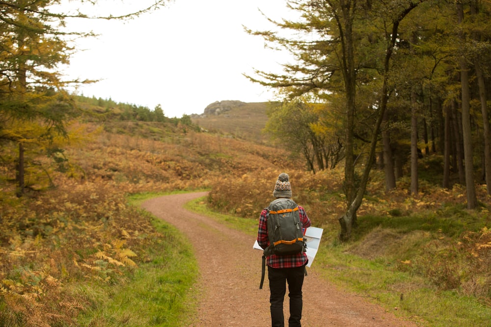 person standing on pathway holding white paper