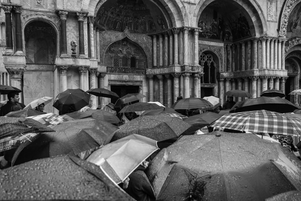 Photo en niveaux de gris de personnes utilisant des parapluies