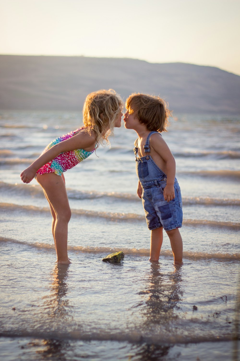 girl and boy kissing on beach during daytime