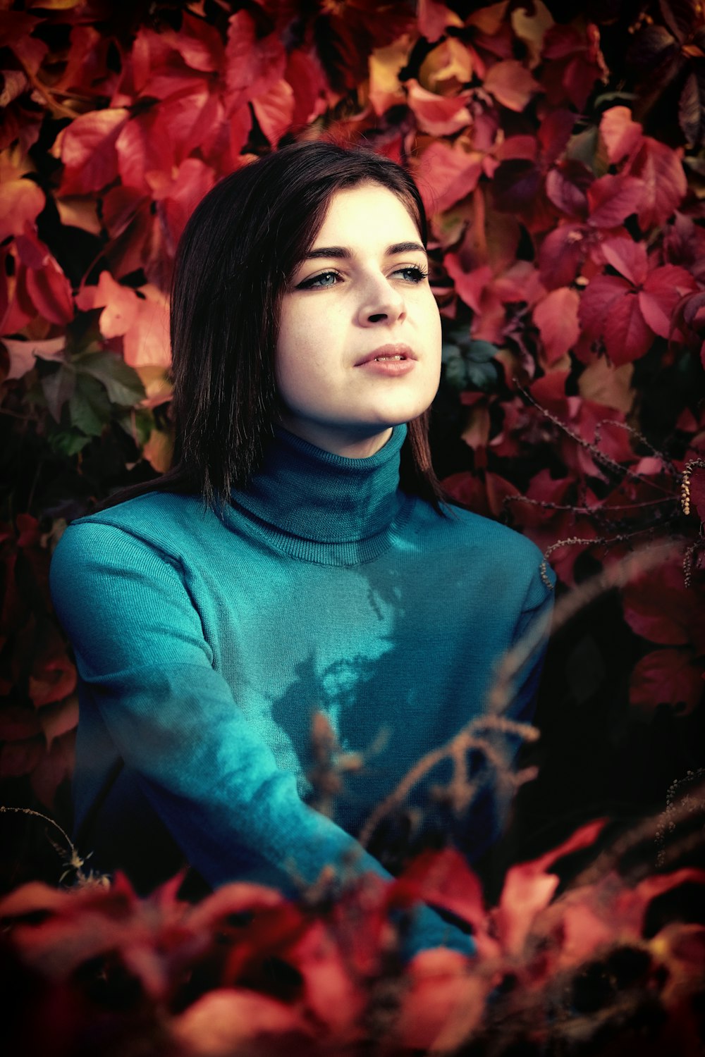 woman sitting near red flower