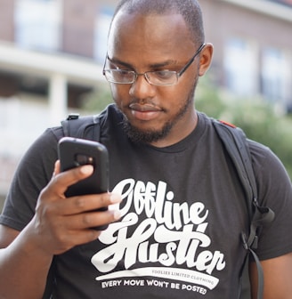 a man wearing glasses looking at his cell phone