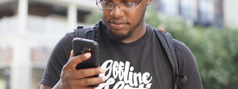 a man wearing glasses looking at his cell phone