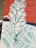 A mural features a stylized depiction of a white flower with blue-green outlines against a vibrant red background. Geometric patterns in light blue and white are interspersed, adding an abstract element to the composition.