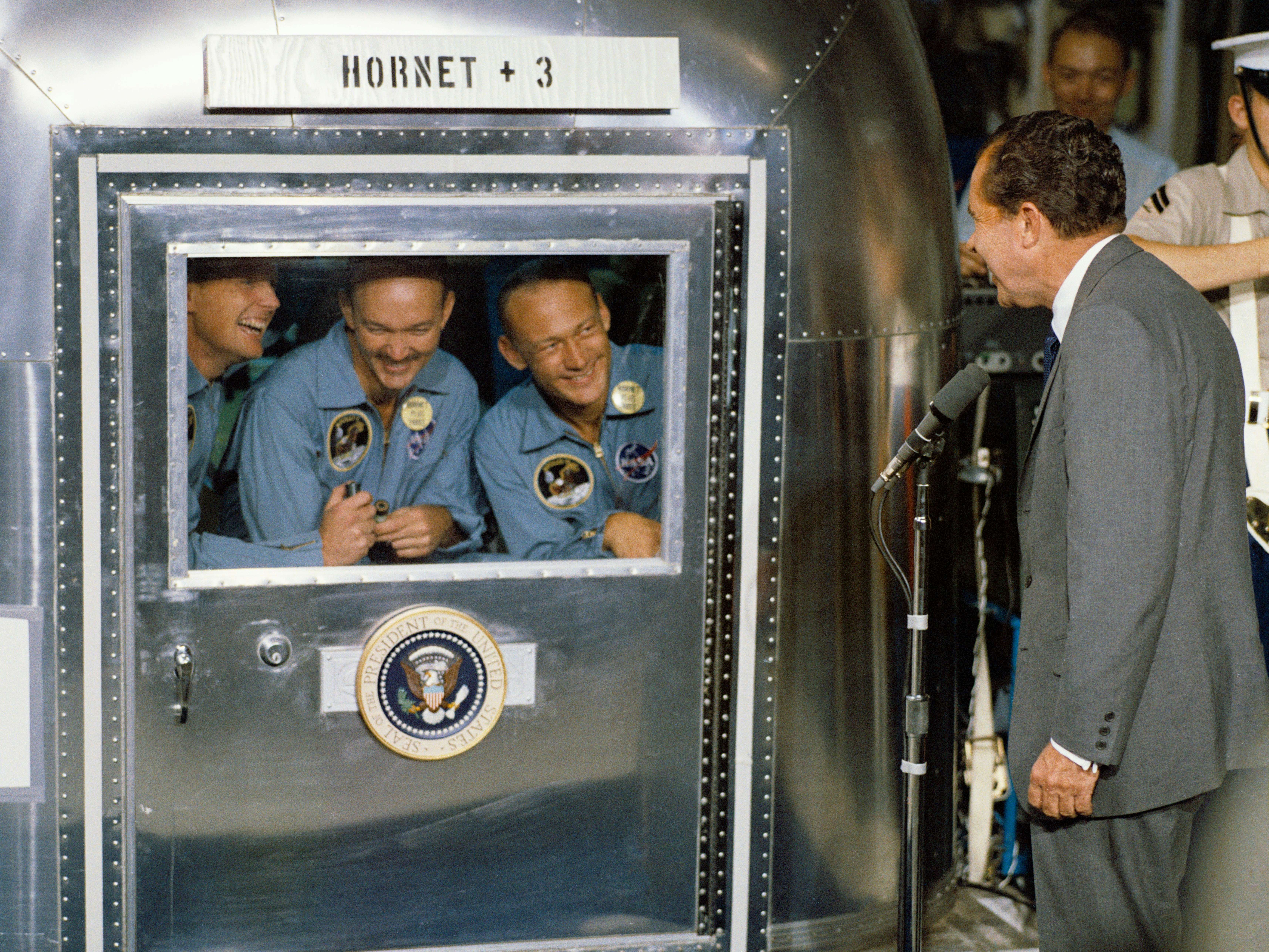 On July 24, 1969, President Richard Nixon welcomes the quarantined Apollo 11 astronauts, Neil Armstrong, Michael Collins, and Buzz Aldrin, aboard the U.S.S. Hornet after the historic Apollo 11 lunar landing mission.