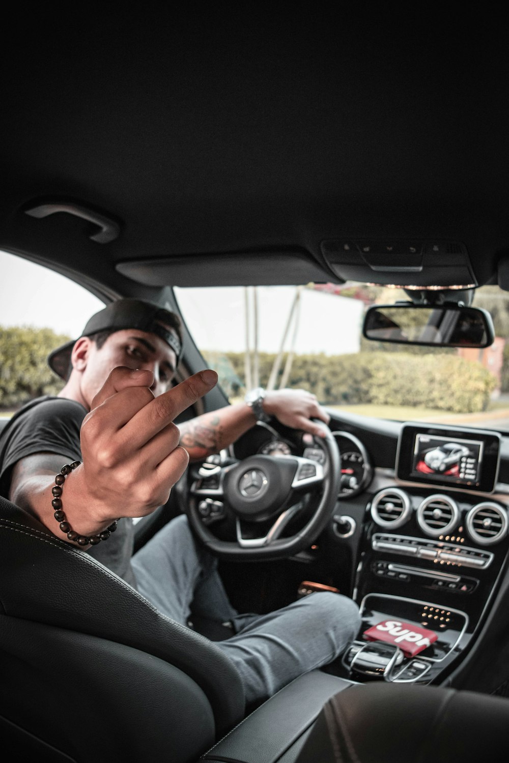 man behind car steering wheel showing his right middle finger