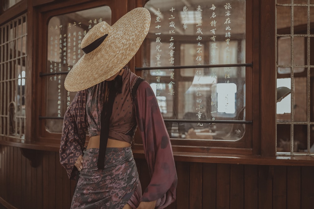 person wearing straw hat standing in front of glass window
