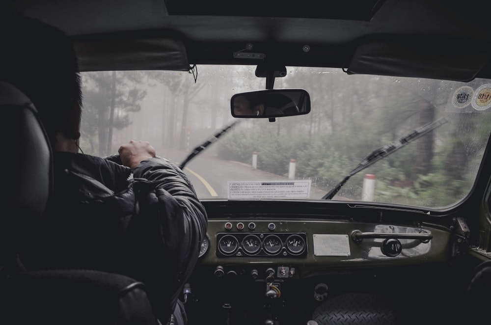 Mann fährt Auto während regnerischer Tageszeit
