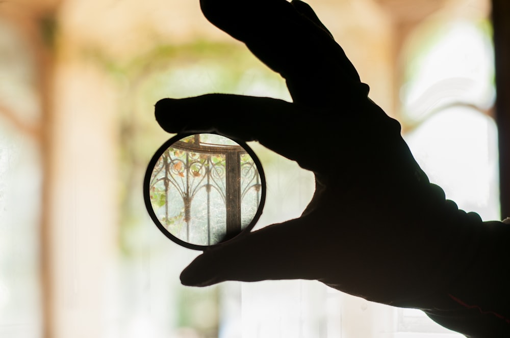 person holding magnifying glass in front of silhouette of two people