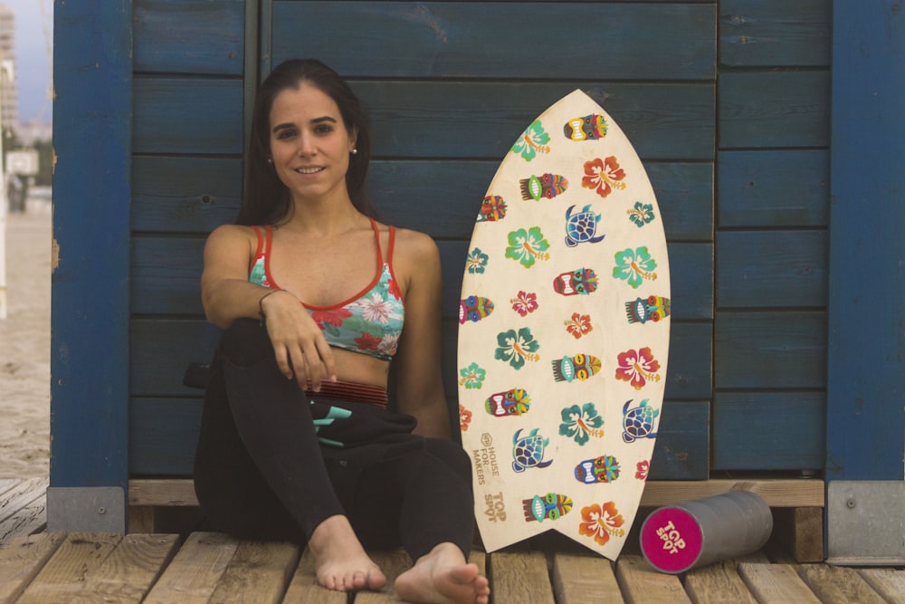 woman sitting on blue surface near skimboard