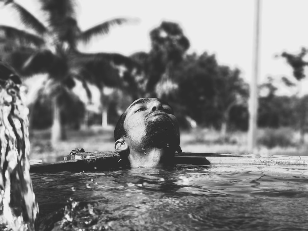 grayscale photography of man on body of water