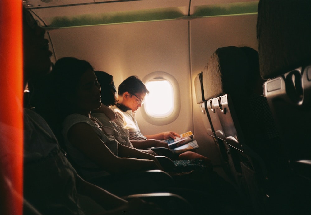 airplane passenger reading book beside the window