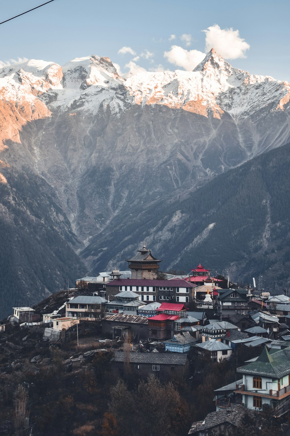 brown and white building near snow-covered mountain during daytime