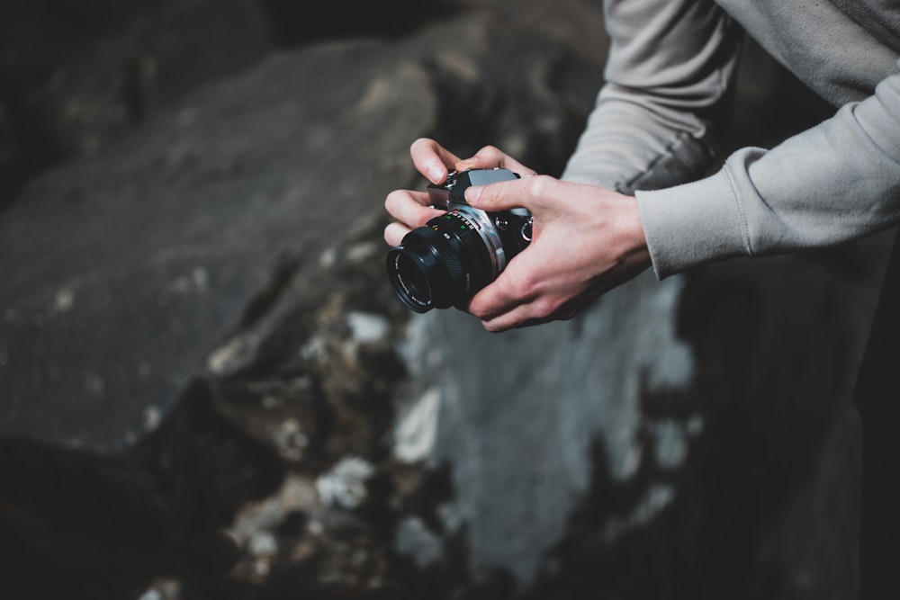 person holding camera by rock