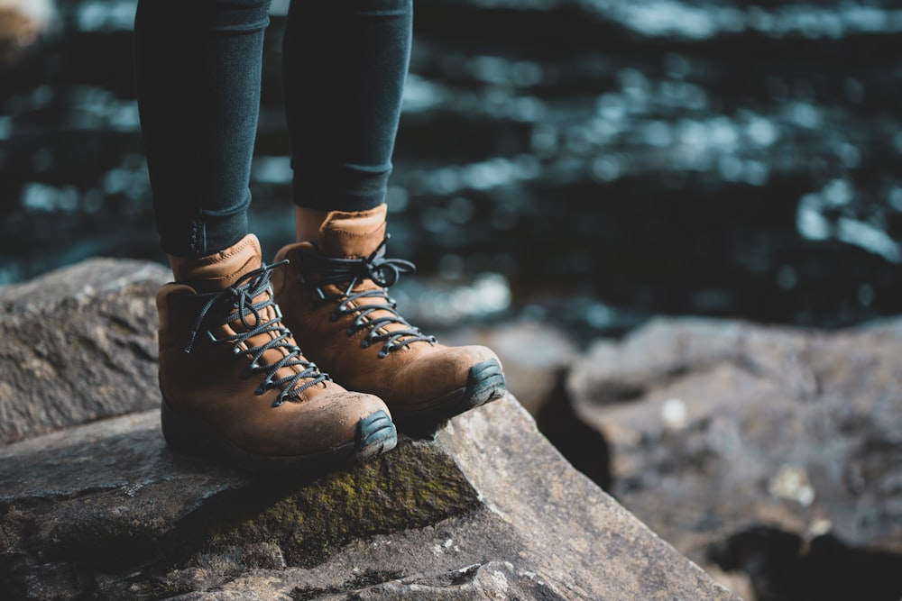 person wearing brown boots standing on rock