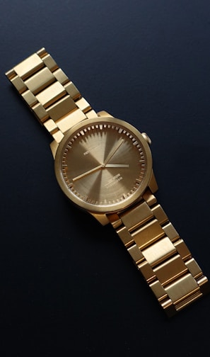 round gold-colored analog watch on black surfac e