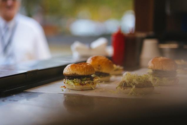 A vibrant kitchen scene with fresh ingredients and a juicy burger being assembled on a white and red themed countertop.