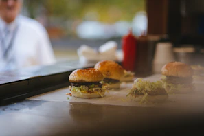 A refrigerated counter displaying fresh ingredients ready for burger assembly.
